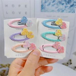 Dettaglio di fermagli per capelli a cuore colorati con glitter su clip avvolte in tessuto