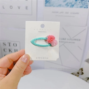 Dettaglio di un fermaglio per capelli in tessuto blu con fiore di tulle rosa su carta