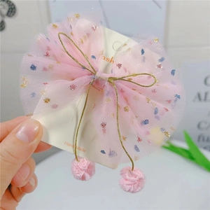 Détail de la pince à cheveux nœud en tulle rose avec pois colorés et pompons doux