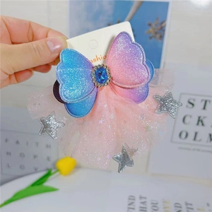 Close-up of sparkling gradient bow hair clip with blue gem and silver glittery stars