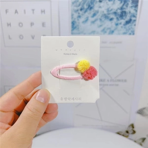 Dettaglio del fermaglio per capelli rosa stile coreano con morbidi pompon gialli e rosa