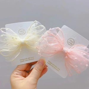 Close-up of pink and beige seersucker bow hair clips with dotted texture and pearls