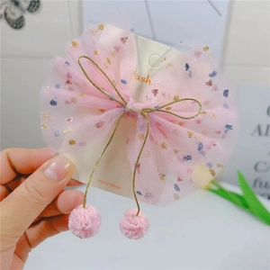 Détail d'un nœud papillon en tulle rose avec paillettes et pendentifs boules dorés