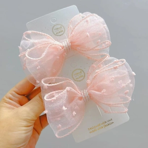 Detail of two-pack pink polka dot seersucker bow clips with delicate pearl center