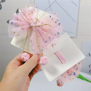 Détail de nœuds en maille rose avec paillettes colorées, nœuds dorés et pompons doux