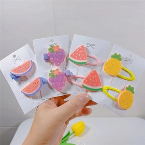 Detail of cute fruit-shaped hair clips for kids featuring watermelon and grape designs
