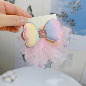 Rainbow gradient bow hair clip with glitter stars, mesh tulle, and a pink faux gemstone centerpiece