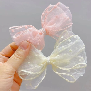 Close-up of seersucker polka dot bow hair clips with pearls in pink and cream white
