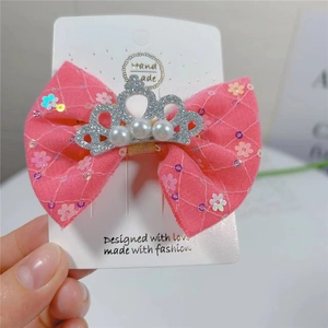 Détail d'une pince à cheveux nœud rose en maille avec couronne argentée et perles blanches