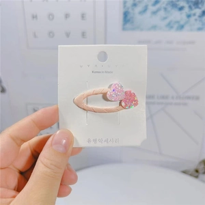 Dettaglio di fermagli per capelli a cuore glitter rosa per bambine su carta