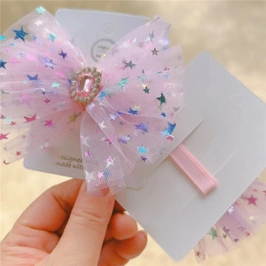Close-up of pink mesh bow hair clip with laser star patterns and a central pink gemstone