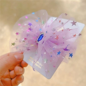 Close-up of purple mesh bow hair clip with colorful stars and a deep blue gemstone