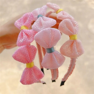 Close-up of glittery pink bow headbands for girls with delicate mesh texture details