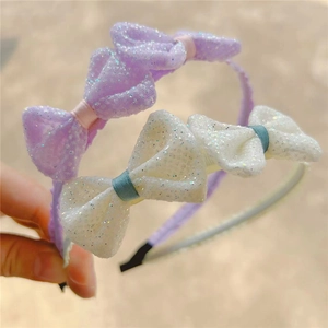 Close-up of sparkling mesh bow headbands for girls in soft purple and white colors