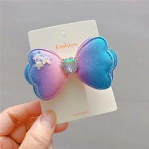Detail of gradient bow hair clip with sparkling stars mesh and heart gemstone