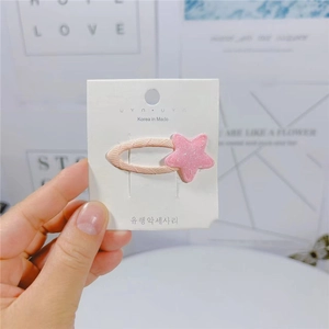 Dettaglio ravvicinato di una clip per capelli a stella glitterata rosa su cartoncino bianco