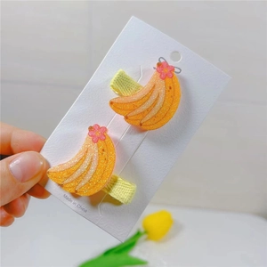 Detail of yellow glitter banana hair clips with pink floral accent and fabric lining