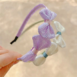 Close-up of glitter bow headbands for girls featuring soft fabric and protective ends