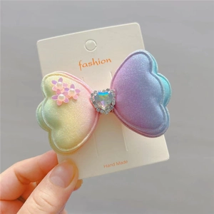 Close-up of glitter bow hair clip with gradient color and heart gemstone detail