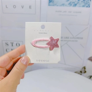 Primo piano di un fermaglio per capelli a stella con paillettes rosa su cartoncino