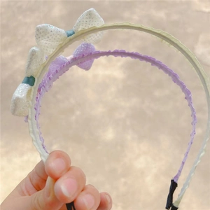 Detail of lavender and white bow headbands with wavy pleated edges for girls