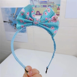 Détail d'un serre-tête bleu ciel à nœud floral avec tissu texturé et motifs roses