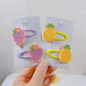 Glittery fruit hair clips for kids featuring grape and pineapple designs on display cards