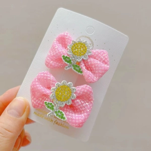 Detail von rosa Haarschleifen mit Sonnenblumen-Strass auf weißer Display-Karte für Kinder