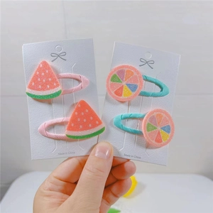 Detail view of cute fruit-themed baby hair clips featuring watermelon and citrus designs