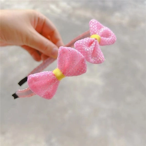 Detail of pink children headband featuring glitter bows and protective black ends