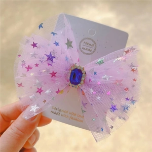 Detail of pink mesh bow hair clip featuring a blue gemstone and silver glitter stars