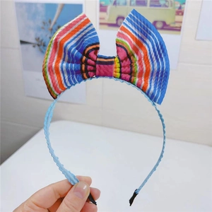 Gros plan sur un serre-tête avec un grand nœud arc-en-ciel coloré et ruban bleu ondulé