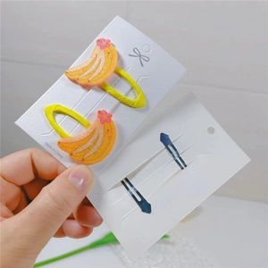 Detailed view of banana-shaped hair clips with yellow glitter and pink floral accents