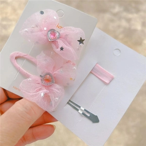 Détail des barrettes nœuds en organza rose avec strass en cœur et petites perles