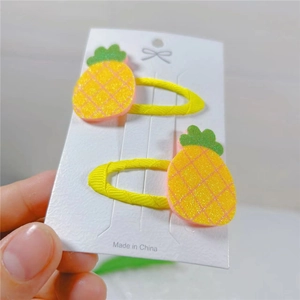 Detail of yellow pineapple hair clips for kids featuring glitter fruit and ribbon wrap