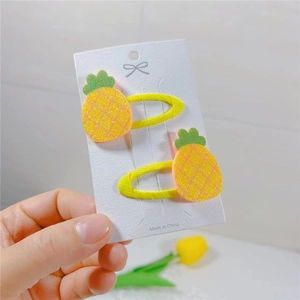 Close-up of yellow glitter pineapple hair clips for kids with green leaf details