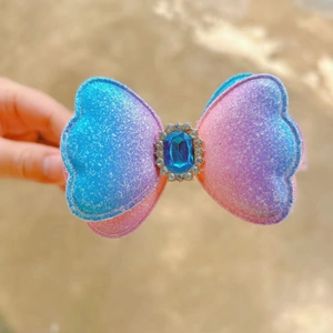 Détail d'un serre-tête nœud à paillettes dégradé bleu-rose avec une grande pierre bleue