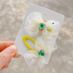 Détail du nœud à cheveux en résille blanche avec cœur vert et perles en forme d'étoile
