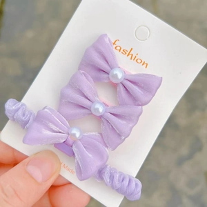 Close-up of three purple organza bow hair clips with pearls on a fashion card