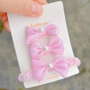 Detail of pink silk bow hair clips and scrunchie set with elegant pearls on card