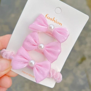 Close-up of pink ribbon hair clips with white pearls on a white display card