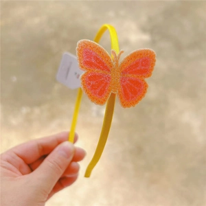 Detailed view of yellow headband with large orange glitter butterfly decoration