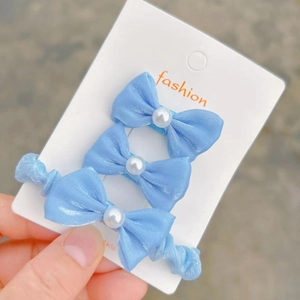 Set of 3 light blue satin bow hair ties with pearl accents on a white display card