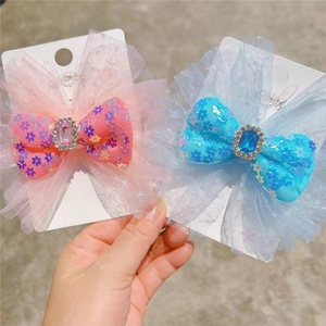 Close-up of sparkling mesh bow hair clips with glitter flower patterns and blue gems