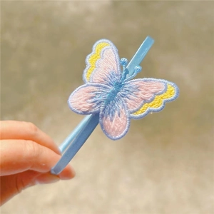 Macro detail of hand-crafted embroidered butterfly on a blue floral girls headband