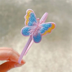 Detailed embroidery of colorful butterfly and pink fabric texture on a girls headband