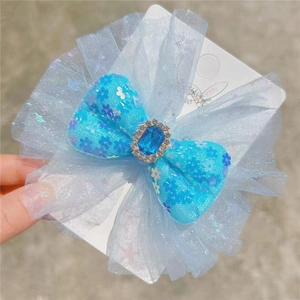 Detail of light blue bow hair clip with sparkling mesh and central blue gemstone accent
