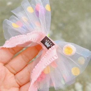 Makro-Detail einer rosa Mesh-Schleife mit bunten Punkten und Kronen-Etikett für Haare