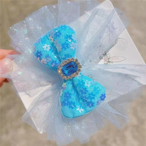 Close-up of blue sequin hair bow with a large crystal gemstone and glitter mesh veil