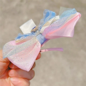 Détail d'un nœud papillon en dégradé rose et bleu avec un ornement en pierre bleue